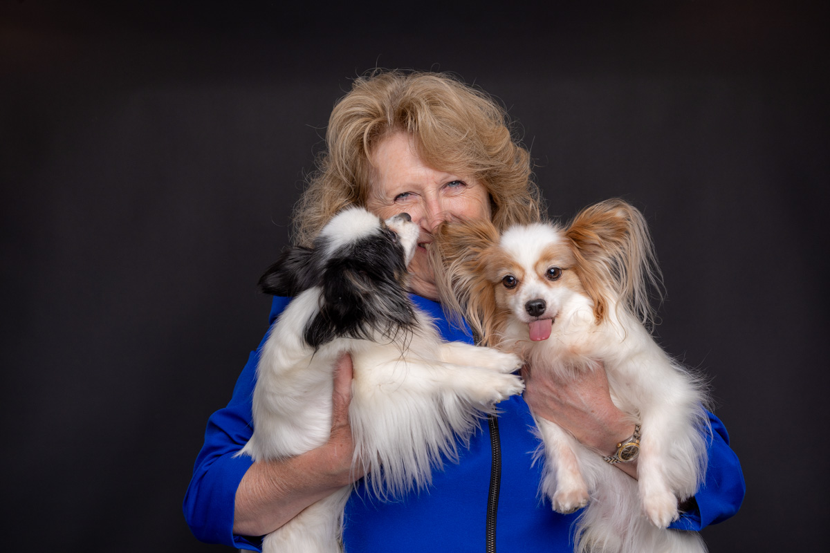 Kelly Arsenault smiling while holding her two Papillons